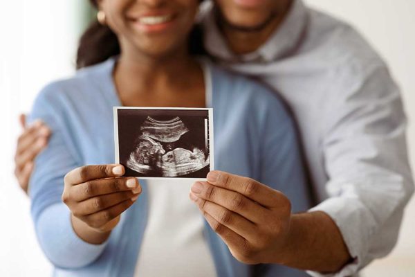 Photo of people holding image of ultrasound of baby in womb
