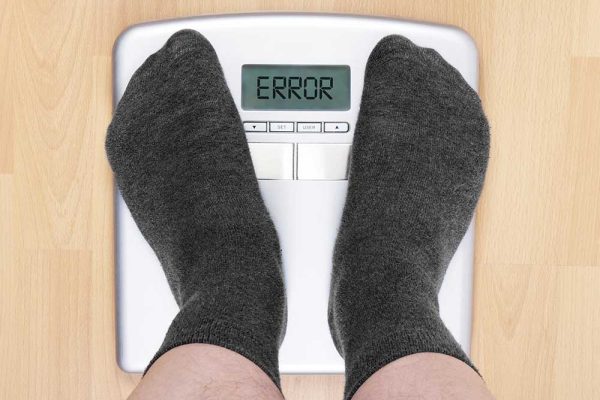 Photo of person's feet on scale, scale has words error instead of weight